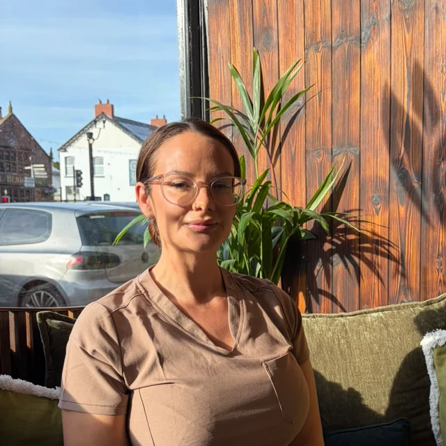 Nicola, therapist at Health Pod Frodsham, sitting by the studio window